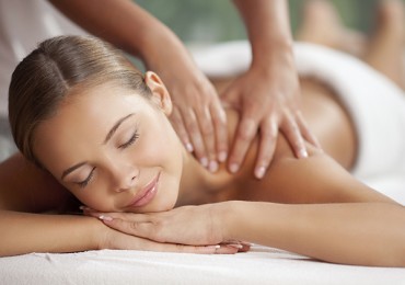 Young happy woman receiving shoulder massage at spa and beauty salon